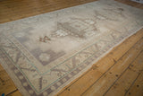 Distressed Oushak rug runner border with geometric guls, ivory, dusty aubergine, and time-softened tones.