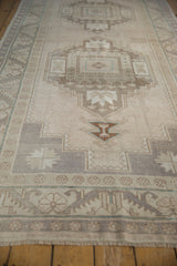 Distressed Oushak rug runner with textured pile and geometric dragon motifs in muted ivory and aubergine.