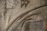 Distressed Oushak runner's textured folds, with faded beige tones and teal lines.