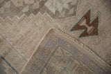 Vintage Distressed Oushak rug detail: brown geometric 'dragon face' motif, turquoise, mauve border, and pile wear.