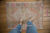 Faded distressed texture of vintage Oushak rug with pale orange and pink florals.