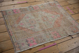 Vintage distressed Oushak rug with geometric floral medallion in soft pale orange and pink.