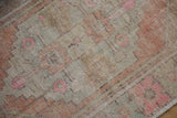 Distressed Oushak rug pile detail, showing geometric floral pink motifs and intact side selvage.
