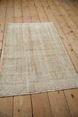 Distressed beige and ivory textured pile of the vintage Oushak rug, with worn fringe.