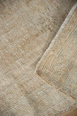 Textural detail of the distressed beige Oushak rug, showing wear to foundation and selvedge.