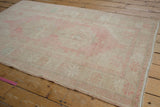 Soft blush pink and pale turquoise motifs on the distressed vintage Oushak rug surface.
