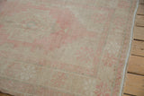 Distressed side selvage, worn low pile, and faded blush pink patterns on the Oushak rug.