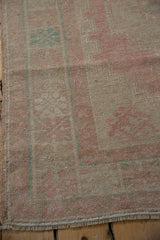 Distressed texture and faded blush pink and pale turquoise motifs on the vintage Oushak rug.