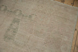 Close-up of distressed Oushak rug pile showing mostly even wear and faint green motifs.