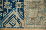 Close-up of distressed Oushak runner showing geometric serrated patterns in indigo blue and pale teal.