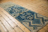 Distressed pile texture shows blue and beige serrated geometric motifs on Oushak runner.