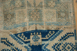 Distressed vintage Oushak rug pile, featuring cobalt geometric forms and muted beige patterns.