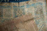 Oushak rug corner shows distressed beige and blue pile, revealing woven foundation and selvage.