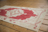 Distressed vintage Oushak rug with abrashed cinnabar red and ivory field, serpent border details.