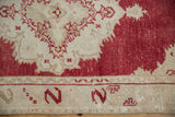 Close-up of vintage distressed Oushak rug's cinnabar field with beige wear and serpent border motif.