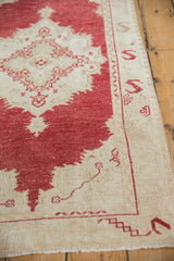 Distressed Vintage Oushak rug pile revealing cinnabar red medallion on ivory field and serpent border.