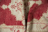 Distressed cinnabar red and sand abrash pile on a folded vintage Oushak rug.