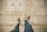 Distressed vintage Oushak rug with faded ivory and pale coffee brown geometric designs.