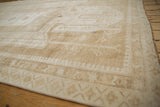 Textural distressed Oushak rug surface with muted ivory and pale coffee brown motifs.