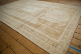 Vintage distressed Oushak rug corner, featuring ivory and beige border motifs.