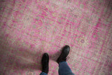 Distressed hot pink fuchsia Sivas rug texture, showing mostly even wear and faded floral vinery.