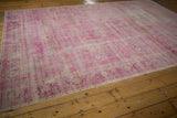 Distressed vintage Sivas carpet corner showing worn hot pink and aubergine floral motifs.