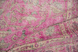 Textured close-up of the distressed vintage Sivas carpet with hot pink fuchsia, ivory, and aubergine florals.