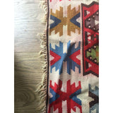 Side detail of vintage Turkish Kilim rug, showing bold geometric patterns and worn fringe.