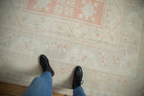 Distressed Oushak rug's even wear, soft ivory, pink grapefruit, and pale slate motifs.