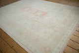 Detail of vintage distressed Oushak carpet pile, showing stepped medallion with pink grapefruit floral motifs.
