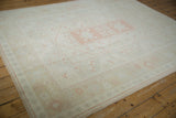 Corner detail of distressed Oushak carpet, showing faded floral patterns and side selvage.