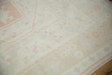 Distressed Oushak carpet pile showing faded ivory, pink grapefruit, and beige floral patterns.