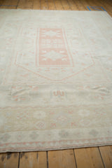 Distressed Oushak carpet pile showing muted pink grapefruit, ivory, and beige floral motifs.