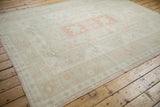 Corner view of distressed Oushak rug showcasing intact side selvage and muted patterns.