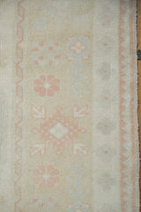 Distressed vintage Oushak carpet detail, showing ivory field, pink grapefruit floral motifs, and even pile wear.