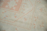 Distressed vintage Oushak rug detail showing pink grapefruit and ivory floral motifs, with even wear.