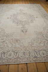 Distressed vintage Sparta carpet corner spandrel with worn silver and beige floral motifs.