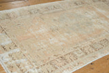 Textural wear on the vintage Oushak rug's faded beige and ivory geometric patterns.