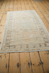 Distressed corner of vintage Oushak rug, showing wear, geometric border, and secured selvage.