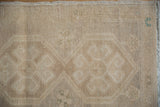 Distressed Oushak rug detail: subtle pinwheel floral motifs in worn beige, antique ivory, and green.