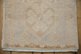 Distressed vintage Oushak rug end, with soft beige tones, subtle floral motifs, and fringe.