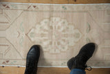 Vintage Distressed Oushak rug's muted ivory field and subtle sea foam green motifs.