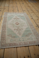 Distressed Oushak rug with softened pile and geometric motifs in ivory, sea foam, pale coffee brown.