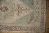 Distressed vintage Oushak rug with ivory field, sea foam green stepped pattern, and brown tendrils.