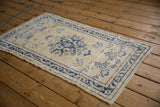 Distressed vintage Oushak rug corner, showing worn navy border and ivory field with visible wear.