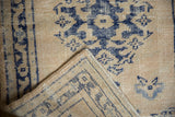 Distressed Oushak rug detail: worn ivory and navy pile, with its woven reverse and selvage.