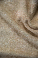 Textured vintage distressed Oushak rug pile, revealing worn ivory and beige fibers and foundation.