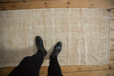 Distressed vintage Oushak runner pile showing even wear in ivory, cream, and beige.