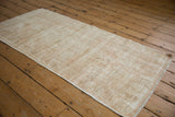 Distressed Oushak runner's textured pile, with ivory and sand tones and even wear.