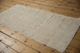 Distressed Oushak rug runner's worn pile, exposed foundation, and intact side selvage.
